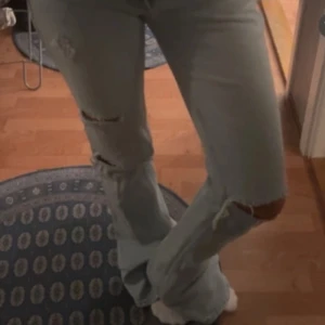 Ljusblå bootcut jeans med slitningar - Säljer ett par ljusblå bootcut jeans från zara i strl 32, dem finns ej att få tag i längre därav priset.❤️de passar någon som är mellan 160-170🥰