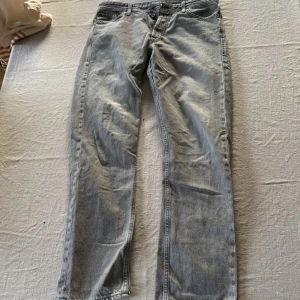 Grå jeans från Jack & Jones, 30/32 - Snygga grå jeans från Jack & Jones i klassisk femficksmodell. Jeansen har raka ben och normal passform, tillverkade i mjukt bomullsjeans-tyg. Perfekta för dig som gillar en avslappnad stil med lite tvättad look.