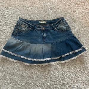 Jeanskjol med volang och spets - En lågmidjad jeanskjol omsydd från ett par jeans. Midjemått tvärsöver - 41cm Längd - 35cm