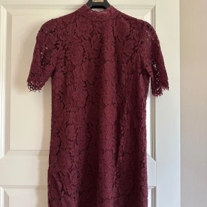 Vinröd spetsklänning Gina Tricot - Vinröd kortklänning i spets med blommigt mönster.