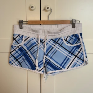 Blå-rutiga shorts från SADS - Supersnygga blå- och vitrutiga shorts från SADS 💙🤍 med elastisk midja och snörning fram. De har vita kanter, praktiska fickor och en sportig, skön passform och är perfekta för varma sommardagar ☀️🌴 Shortsen är i fint skick och väldigt bekväma, men säljs eftersom de tyvärr är för små för mig 💕 Storlek S enligt lappen, men skulle säga att de passar XS till liten S.  📍 Möts upp i Umeå eller skickar mot fraktkostnad 🫶🏻 💸 Pris: 65 kr (kan såklart diskuteras) 