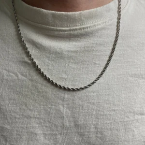 Stainless steel tvinnat halsband - Snyggt halsband i silverfärg med tvinnad kedja som ger en stilren och modern look. Stainless steel, osäker på märke. Helt ny 