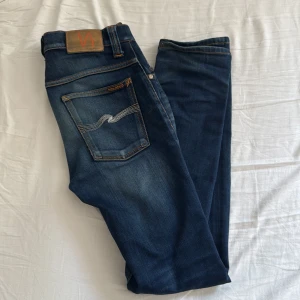Mörkblå jeans från Nudie Jeans - Snygga mörkblå jeans från Nudie Jeans. Riktigt sköna jeans. Säljer för de blivit för små för mig i midjan. Storleken är W28/L32