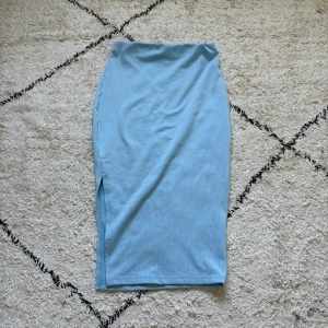 Ljusblå ribbad långkjol från SHEIN - Säljer en ljusblå ribbad långkjol från SHEIN. Kjolen har en tight passform och en liten slits på sidan för extra vibe. Perfekt att styla med en crop top eller oversized hoodie. Enkel och stilren design som är superenkel att matcha.