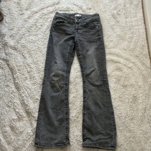 Grå bootcut jeans från Gina Tricot - Snygga grå jeans från Gina Tricot i bootcut-modell. Jeansen har klassisk femficksdesign, coola bakfickor med lock och knapp samt normal passform. Materialet är jeans i bomullsmix och färgen är tvättad grå med lite slitningseffekt.