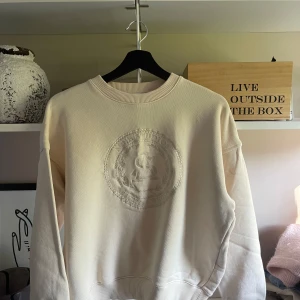 Beige sweatshirt från Acne Studios XS - Snygg beige sweatshirt från Acne Studios i 100% bomull. Tröjan har broderad logga framtill i samma färg. Klassisk rund halsringning och ribbade muddar. 