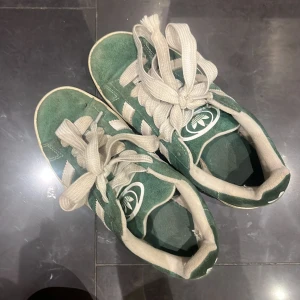 Adidas Campus gröna sneakers mocka - Gröna Adidas Campus sneakers i mocka med vita detaljer och klassiska tre ränder på sidorna. rund tå och breda vita snören. Adidas logga syns både på häl och plös. Perfekta för dig som gillar sköna skor som både går att gå i och springa i!💋 passar 36-37 ungefär