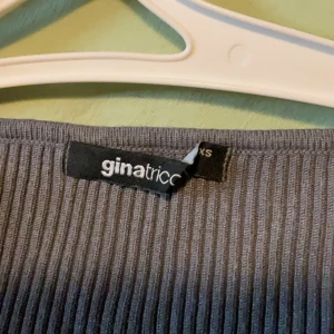 Grå ribbad topp från Gina Tricot - Supersnygg grå ribbad topp från Gina Tricot i storlek XS. Med lång ärm och har en snygg v-ringad halsringning. Perfekt att styla med jeans eller kjol för en trendig look.