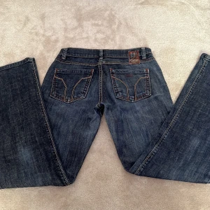 Mörkblå Miss Sixty jeans lågmidjade bootcut - Snygga mörkblå jeans från Miss Sixty med bootcut passform. Jeansen har dragkedja och knapp framtill och är tillverkade i slitstarkt denimtyg. Lågmidjade w25 lite långa på mig som är 163. Skriv för mer frågor💕nypris 2600kr