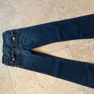 Low flare jeans - Säljer ett par mörkblå low waist flare jeans från Gina Young i storlek 164. Jeansen har kontrastsömmar med snygga detaljer på bakfickorna. Säljer då dem är för korta och inte kommer till användning.Nypris är 360 kr och jeansen är använda ett antal gånger men inget som syns! 