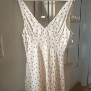 Sommarklänning jordgubbar zara - Supersöt vit kortklänning med små röda jordgubbar över hela tyget. Klänningen har v-ringning, breda axelband och en lätt utställd passform. Perfekt för sommarens varma dagar. Helt slutsåld och populär! Storlek XL men omsydd rejält för att passa en s/m. Använd 2 ggr så den är i nyskick!