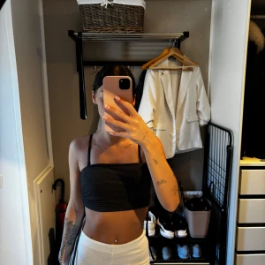 Svart croppad topp från SHEIN - Svart croppad topp från SHEIN, snygg snörningsdetalj i sidan. Toppen är figurnära och har en enkel, stilren look som passar perfekt till höga byxor eller kjol. Materialet är mjukt och stretchigt för en bekväm känsla.