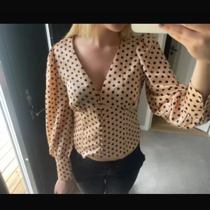 Prickig beige blus med v-ringning - Supersnygg beige blus med svarta prickar och v-ringning. Så gott som i nytt skick. 