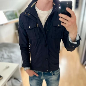 J.lindeberg Field Jacket - Bra skick, använd men inga stora defekter. Storlek S passar dig som är mellan 175-185. Nypris ca 3500kr. Modellen är 185 cm, 79 kg. Det är en tunnd jacka utan foder. Passar bra nu till sen sommar/höst. Skriv för mer information!🤝 