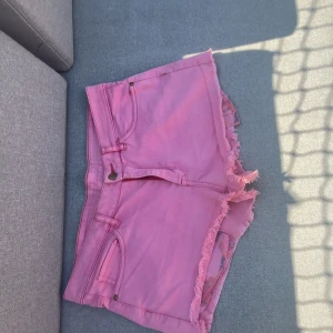 Rosa jeansshorts från MANGO Jeans - Snygga rosa jeansshorts från MANGO Jeans i klassisk femficksmodell. Shortsen har råa, fransiga benslut och dragkedja framtill. Storlek 38/S. Perfekta för sommardagar när du vill sticka ut lite extra. Färgen är en härlig ljusrosa ton.