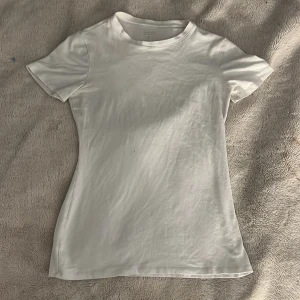 Vit t-shirt från Intimissimi i bomull - vit t-shirt från Intimissimi, Modellen är figurnära med rund halsringning och korta ärmar. Den har en liten fläck som knappt synns som jag tyvärr inte fått bort