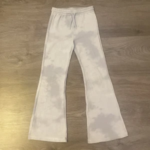 Mjukisbyxor med snören från Kappahl - Säljer ett par ljusblå mjukisbyxor med vita moln liknande detaljer. De har snören framtill men inga fickor. Passar dig som gillar bootcut.