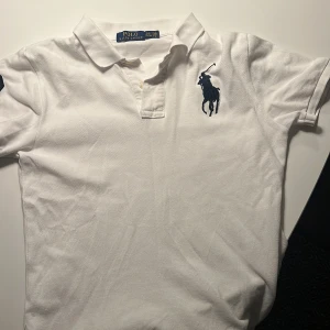 Vit slim fit piké från Polo Ralph Lauren - Jag säljer en vit pikétröja från Polo Ralph Lauren i slim fit-modell. Klassisk krage, korta ärmar och broderad marinblå logga på bröstet samt en stor siffra 3 på ärmen. Nypris är ca 1000 kr och mitt pris är 210 kr. Den är i storleken L/G (14-16) i barnstorlek och det motsvara ungefär S i herrstorlek. Perfekt för en stilren look. Skriv bara vid minsta fråga, priset kan diskuteras!