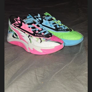 Färgglada sneakers från 2K ZEROS - Säljer ett par unika basket sneakers från 2K ZEROS med coola färgblock i rosa, blått, grönt och svart. Skorna har snörning och en chunky sula. Perfekta för dig som vill sticka ut med din stil och gillar färgstarka detaljer.