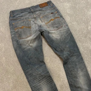 Nudie jeans - Tja! Säljer dessa asfeta ljusblå/grå Nudie jeansen med riktigt najs tvätt! Slimfit passform. Jeansen är i gott skick, syns att de använts men på ett snyggt sätt! Size 32/34. Skriv vid frågor! 