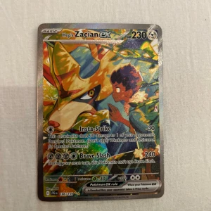 Pokémonkort Hop's Zacian ex 230 HP - Säljer ett holografiskt Pokémonkort: Hop's Zacian ex med 230 HP. Kortet har färgstark design med Zacian och Hop, samt attacker som Insta-Strike och Brave Slash. Kortet är från Scarlet & Violet-serien, nummer 186/159.