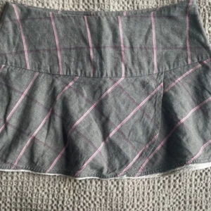 Grå rutig kjol från att. - Grå kortkjol från att. med rosa och lila rutor. Kjolen har en lätt utsvängd form och är perfekt för dig som gillar en klassisk men ändå trendig stil. Tunt och mjukt material som känns bekvämt hela dagen. Säljer då den var lite för liten för mig som vanligtvis har strl 34-36.