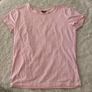 Ljusrosa t-shirt - En ljusrosa t-shirt med rund halsringning och korta ärmar. 