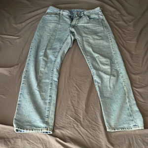 Ljusblå jeansbyxor från Vaillent - Säljer ett par ljusblå jeansbyxor från Vaillent. Klassisk femficksmodell med raka ben och normal passform. Byxorna har gylf med dragkedja och knapp samt läderpatch med logga bak i midjan.