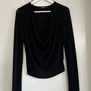 Svart långärmad topp med draperad urringning från BikBok - Säljer en svart långärmad topp från BikBok med snygg draperad urringning. Toppen har en elegant och stilren look. Kan användas både bak och fram. Aldrig använd.