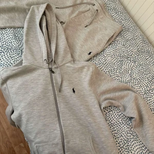 Grå mjukisbyxor från Polo Ralph Lauren - Säljer ett par grå mjukisbyxor från Polo Ralph Lauren med dragsko i midjan och broderad logga på benet. Byxorna har en avslappnad passform och är perfekta för chill dagar.Om du vill ha byxorna för sig och tröjan för sig kan vi diskutera pris .Annars kostar den 1400kr .Den är nästan helt ny.