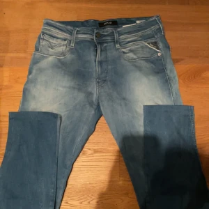 Replay ljusblå jeansbyxor - Säljer ett par ljusblå jeansbyxor från Replay med klassisk femficksdesign och dragkedja. Byxorna har raka ben och diskreta slitningar framtill för en avslappnad look. Perfekta för dig som gillar stilrena och bekväma jeans.