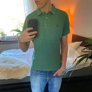 Grön pikétröja från Ralph Lauren - Säljer en sjukt snygg och klassisk grön pikétröja från Polo Ralph Lauren med krage och knappar framtill. Tröjan har korta ärmar och den ikoniska broderade loggan på bröstet. Perfekt till jeans eller shorts och fungerar sjukt bra nu i sommar! Passformen är Classic fit och befinner sig i skick 8/10. Tröjan är använd men fortfarande i väldigt bra skick. Tveka inte på att höra av dig vid frågor eller funderingar! ⭐️