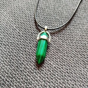 Halsband med grön kristallhänge - Snyggt halsband med ett spetsigt grön- och svartmönstrat kristallhänge. Hänget sitter i ett silverfärgat fäste. Perfekt för dig som gillar unika smycken med naturinspirerad känsla. Ej äkta kristall.