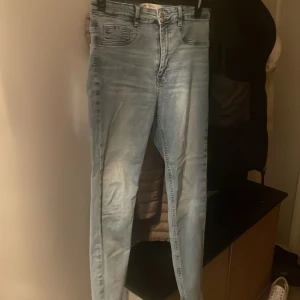 Ljusblå skinny jeans - Säljer ett par ljusblå skinny jeans med klassisk femficksdesign och hög midja. Jeansen har en lätt tvättad look och smal passform hela vägen ner. Perfekta till sneakers eller boots.
