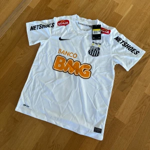 Neymar santos tshirt - Säljer en vit Santos FC matchtröja från Nike med Neymar Jr och nummer 11 på ryggen. Tröjan har klubbmärke, sponsorer och svarta detaljer. Klassisk rund hals och korta ärmar. Etiketten är fortfarande på.