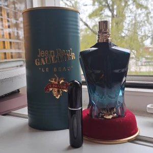 5m av Jean Paul Gaultier Le Beau Le Parfum herrparfym - Jean Paul Gaultier Le Beau Le Parfum i en snygg blågrön flaska formad som en manlig torso med gulddetaljer. Kommer med originalförpackning i grön tub och röd sammetsbas. En extra svart resespray medföljer.