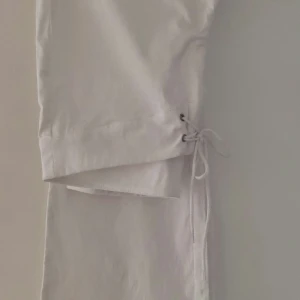 Vita bootcut byxor med snörning storlek 42 Medium. - Säljer ett par vita bootcut byxor med snörning fram och i benslut. Byxorna har en snygg tight passform och är perfekta för dig som gillar en stilren look med lite extra detalj. Materialet  är strechigt mjukt och bekvämt. Från rök och djurfritt hem.