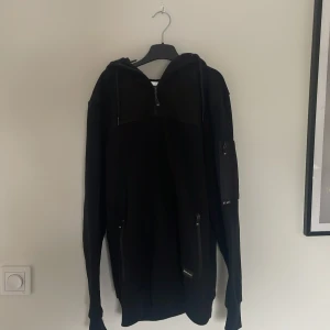 Svart hoodie från Nannystate st.S - Säljer en svart hoodie från Nannystate i storlek small. Tröjan har dragkedja framtill, huva med snörning och fickor med dragkedja. Perfekt för en avslappnad stil och passar bra till vardags. Materialet känns mjukt och bekvämt.