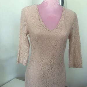 Rosa spetsklänning från Saint Tropez - Säljer en elegant rosa spetsklänning från Saint Tropez med v-ringning och trekvartsärm. Klänningen har ett vackert blommigt spetsmönster och är fodrad i matchande färg. Perfekt för dig som gillar en feminin och stilren look. Mjuk spets 