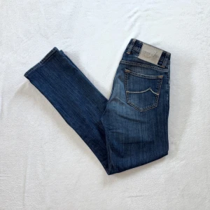 Blå jeans från Jacob Cohen - Säljer ett par klassiska blå jeans från Jacob Cohen med raka ben och snygga slitningar. Jeansen har fem fickor och hästskinnspatch där bak. Lång W30, eftertraktad modell. Har du några funderingar eller liknande så är du mer än välkommen att fråga!