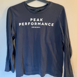 Mörkblå långärmad tröja från Peak Performance - Säljer en mörkblå långärmad tröja från Peak Performance med vit logotyptext på bröstet. Säljer den då den är för liten för mig, men dock inte använt många gånger. Tröjan har rund halsringning och är tillverkad i mjuk bomull. Den har ett litet hål på armen men syns inte när man har på den💗