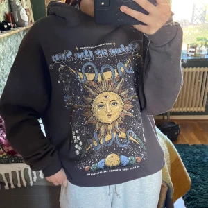 Hoodie med tryck från Pull&Bear - Mörk grå hoodie med tryck på framsidan som säger ”Shine as the sun” med en sol, från Pull&Bear. Knappt använd, bra skick, väldigt mjuk på insidan, storlek L. 