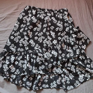 Svart blommig kjol från Pernilla Wahlgren -  Kjolen har volangdetaljer och resår i midjan. 