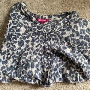 mönstrad blus från Indiska - Säljer en snygg leopardmönstrad klänning från Indiska i storlek M. Klänningen har v-ringning och är i ett mjukt, lätt tyg med blå och grå toner. Perfekt för dig som gillar djurmönster och vill sticka ut.