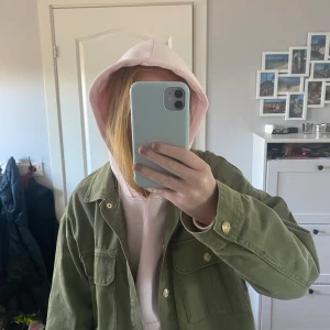 Jeansjacka  - Säljer en grön jeans jackafrån Zara med klassisk krage och knappar framtill. Jackan har två bröstfickor med lock och guldiga knappar. Perfekt att slänga över en hoodie för en avslappnad look.