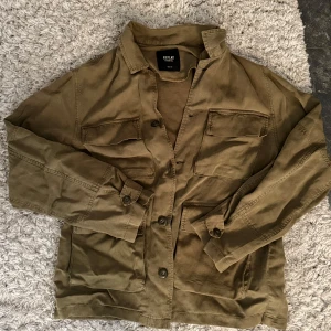 Olivgrön overshirt från Replay - Säljer en olivgrön overshirt från Replay med två stora bröstfickor och knäppning framtill. Jackan har en avslappnad passform och är tillverkad i bomull. Perfekt att slänga över en t-shirt eller skjorta! Den är i tunt tyg så funkar perfekt till våren och sommaren! Köpt för 2200kr ny och har inga defekter!