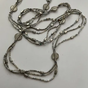 Långt halsband med silverfärgade detaljer - Säljer ett långt halsband med flera rader små silverfärgade pärlor och dekorativa runda detaljer. Halsbandet har en bohemisk känsla och kan bäras både enkelt och dubbelt runt halsen. Perfekt för att ge din outfit lite extra glans.