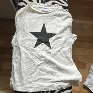 Vit t-shirt med svart stjärna från Gina Tricot - Vit t-shirt från Gina Tricot med en stor svart stjärna tryckt på framsidan. Klassisk rund halsringning och rak passform. Perfekt för en enkel och stilren look. Använd få antal gånger då den inte riktigt har vartit min stil