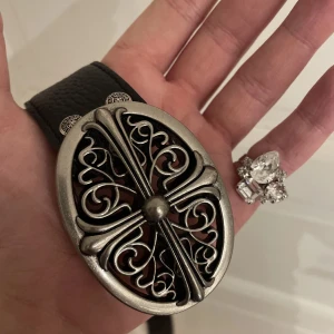 Chrome Hearts Oval Buckle Belt - Snyggt svart bälte från Chrome Hearts med ett detaljerat, ovalt spänne i silverfärg. Bältet har ett präglat mönster och är perfekt för en unik outfit.🐉💴😝Bältet kommer ifrån Minato City, Tokyo Japan. 🇯🇵 