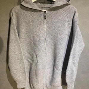 Grå stickad hoodie med dragkedja - Säljer en stilren grå stickad hoodie med dragkedja. Perfekt för kyliga dagar med sin mjuka och bekväma passform. Tveka inte att kontakta vid frågor och funderingar materialet är ull